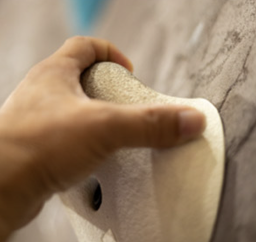Close-up of a hand gripping a climbing hold on an indoor climbing wall.